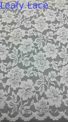 Tejido de encaje de estiramiento completo en blanco, adornado con delicados patrones florales y bordes con gavillas lujosamente