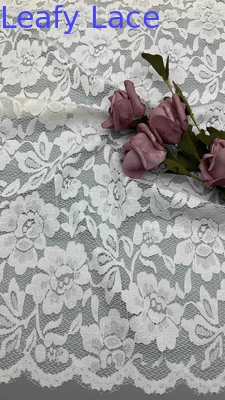 Tejido de encaje de estiramiento completo en blanco, adornado con delicados patrones florales y bordes con gavillas lujosamente