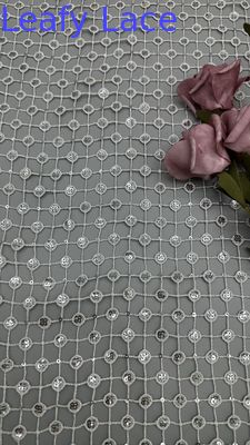 Tela con detalles de lentejuelas plateadas, calada y a cuadros blanco y negro, ideal para vestidos formales llamativos