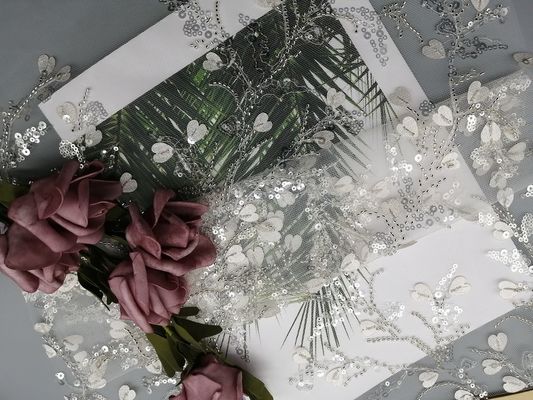La lentejuela blanca de la ropa femenina ata la tela moldeada del bordado